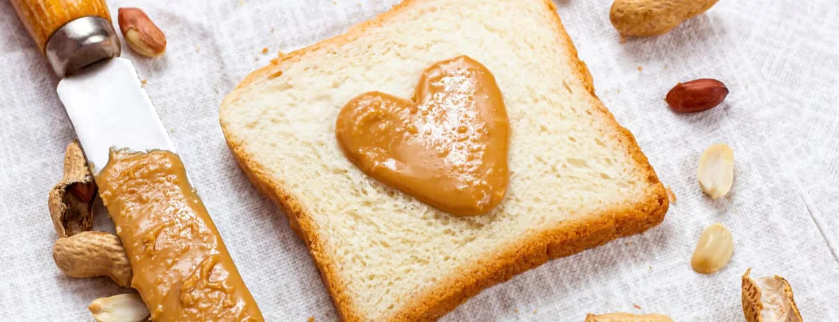 A piece of toast with peanut butter shaped like a heart